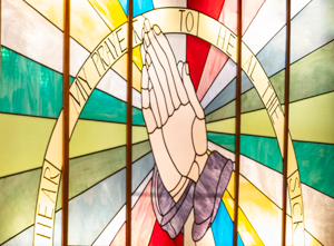 Stained glass hands in prayer. Photo by Briana Cummings.